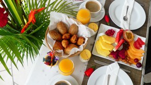 Une table dressée pour le petit-déjeuner, avec des croissants, des fruits et des boissons.