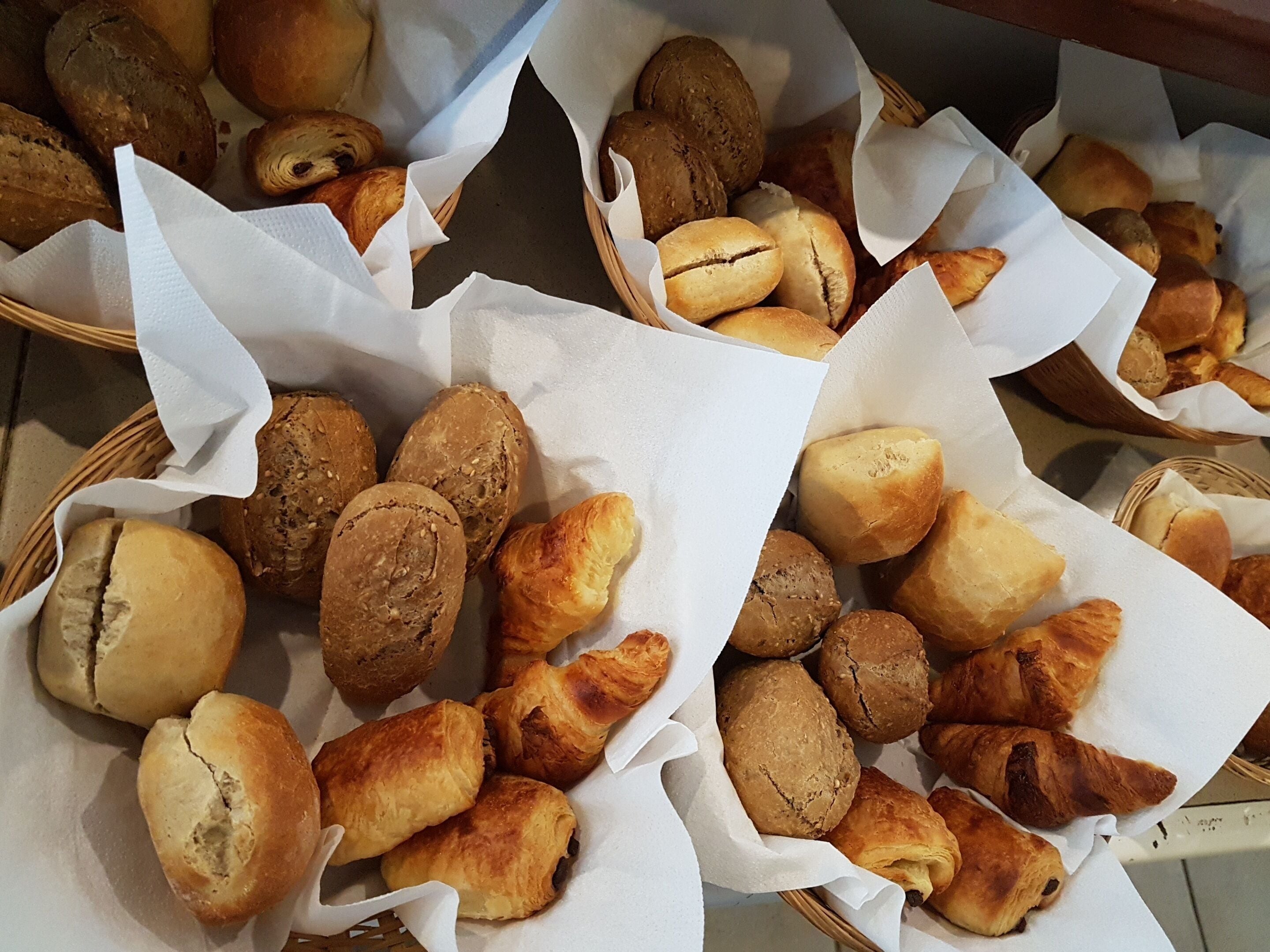 Körbe mit verschiedenen Backwaren, vermutlich Brot und Gebäck, auf einem Tisch drapiert.