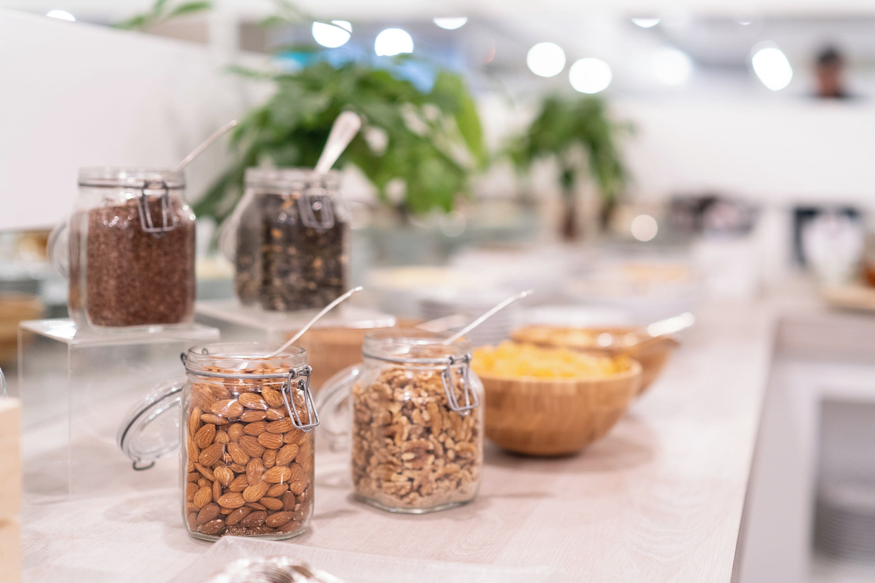 A buffet with various food items in glass jars and a wooden bowl.