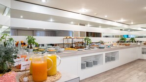 Un buffet de petit-déjeuner moderne, proposé dans un hôtel, avec un large choix d’aliments et de boissons, notamment des fruits, des viennoiseries et des jus de fruits.