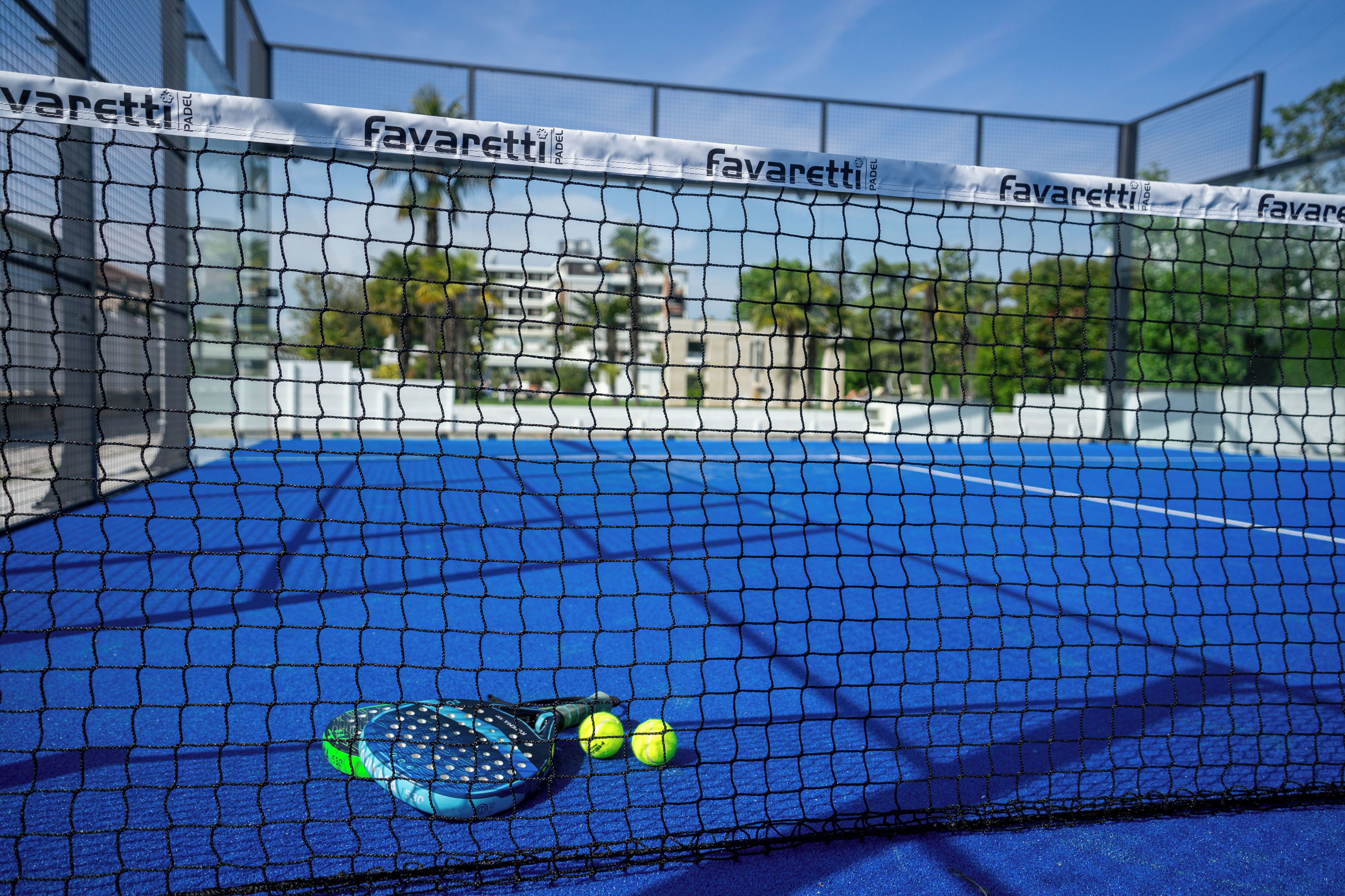Un court de tennis avec un filet, une raquette de tennis et des balles de tennis.