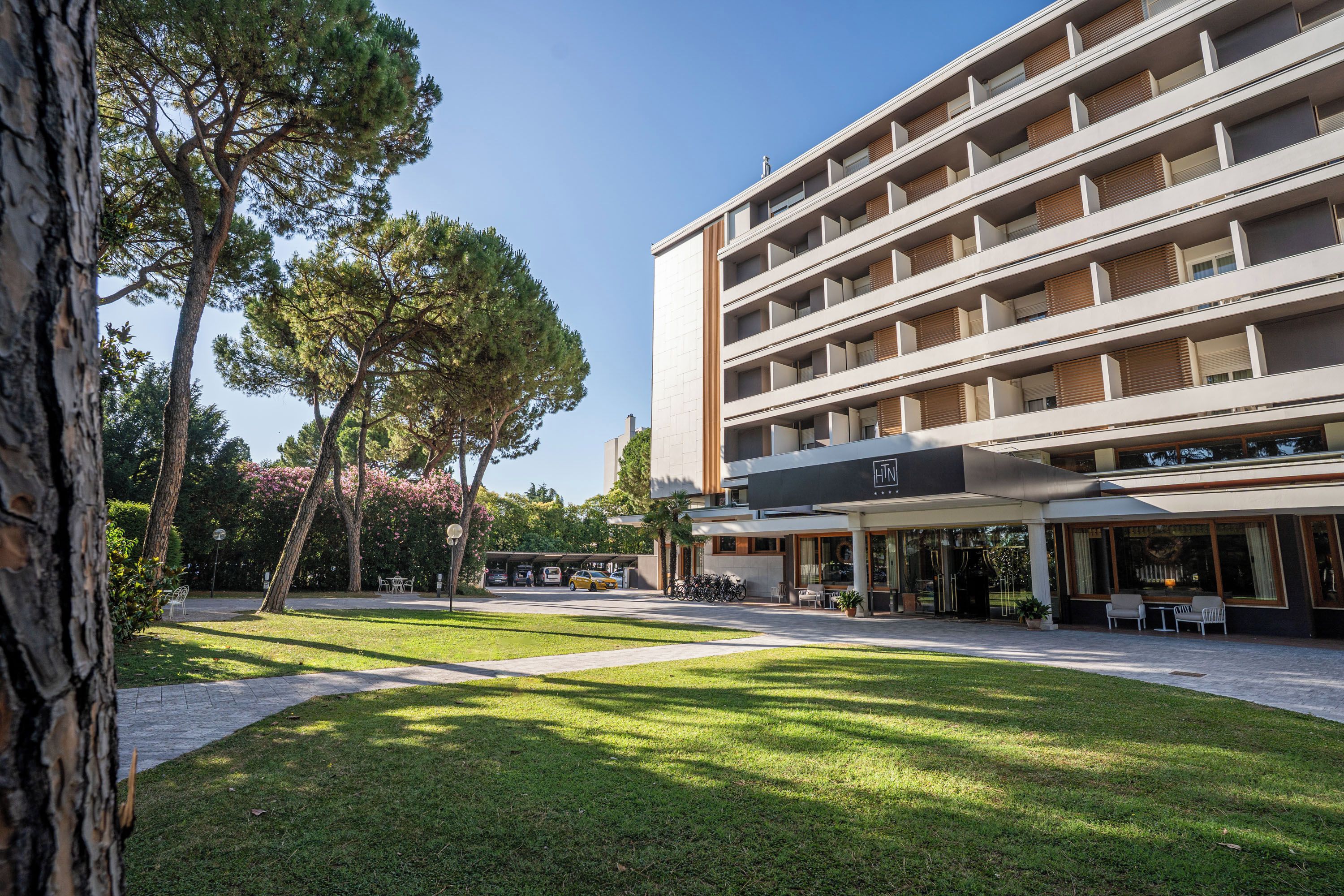 A multi-story hotel with a covered outdoor seating area and a parking lot.