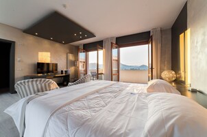 Habitación de hotel moderna con una cama grande, televisor, escritorio y vistas a la montaña.