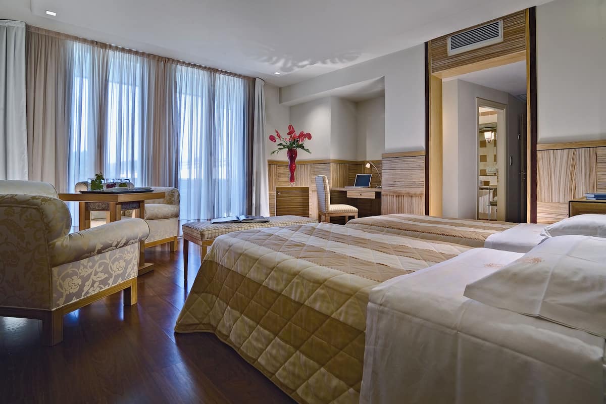 Ein Hotelzimmer mit einem großen Bett, einem Schreibtisch, einem Stuhl und einem Schminktisch mit Spiegel.