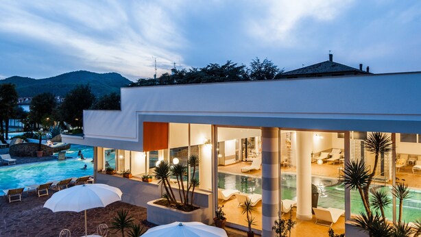 Un hôtel moderne doté d’une piscine, de chaises longues et offrant une vue sur les montagnes.