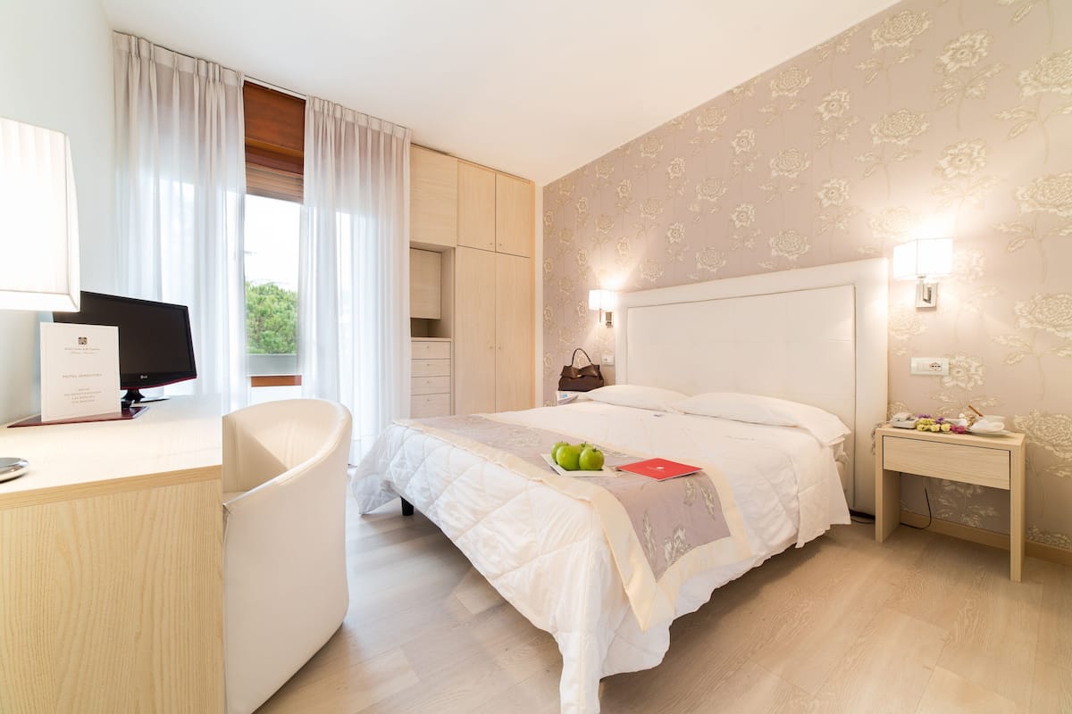 Ein Hotelzimmer mit Bett, Schreibtisch, Stuhl, Nachttisch und einer Wandleuchte.