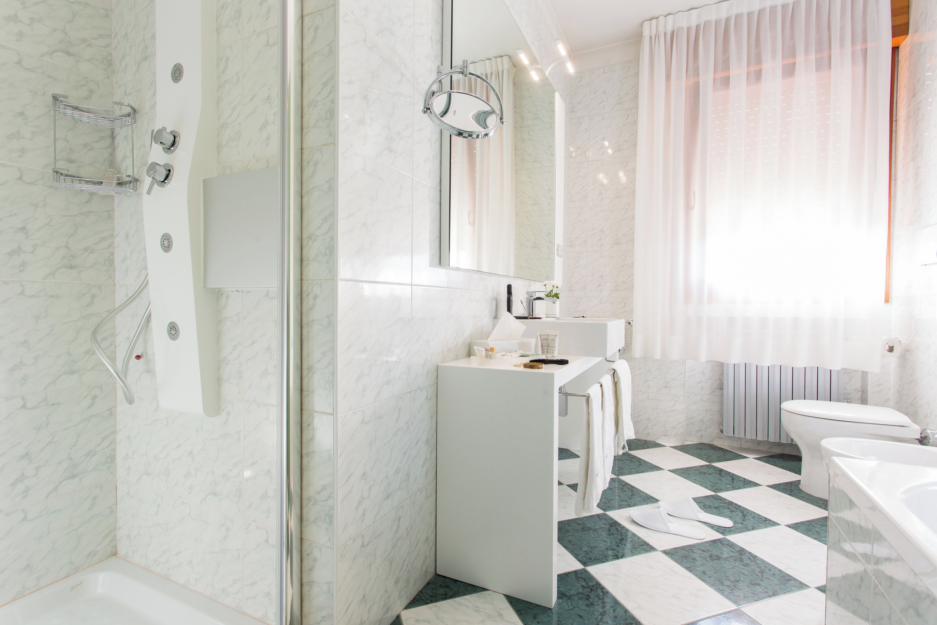 Un baño moderno con ducha, lavamanos, inodoro y un espejo grande.