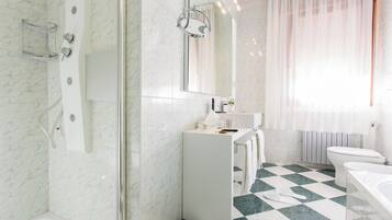 Un baño moderno con ducha, lavamanos, inodoro y un espejo grande.