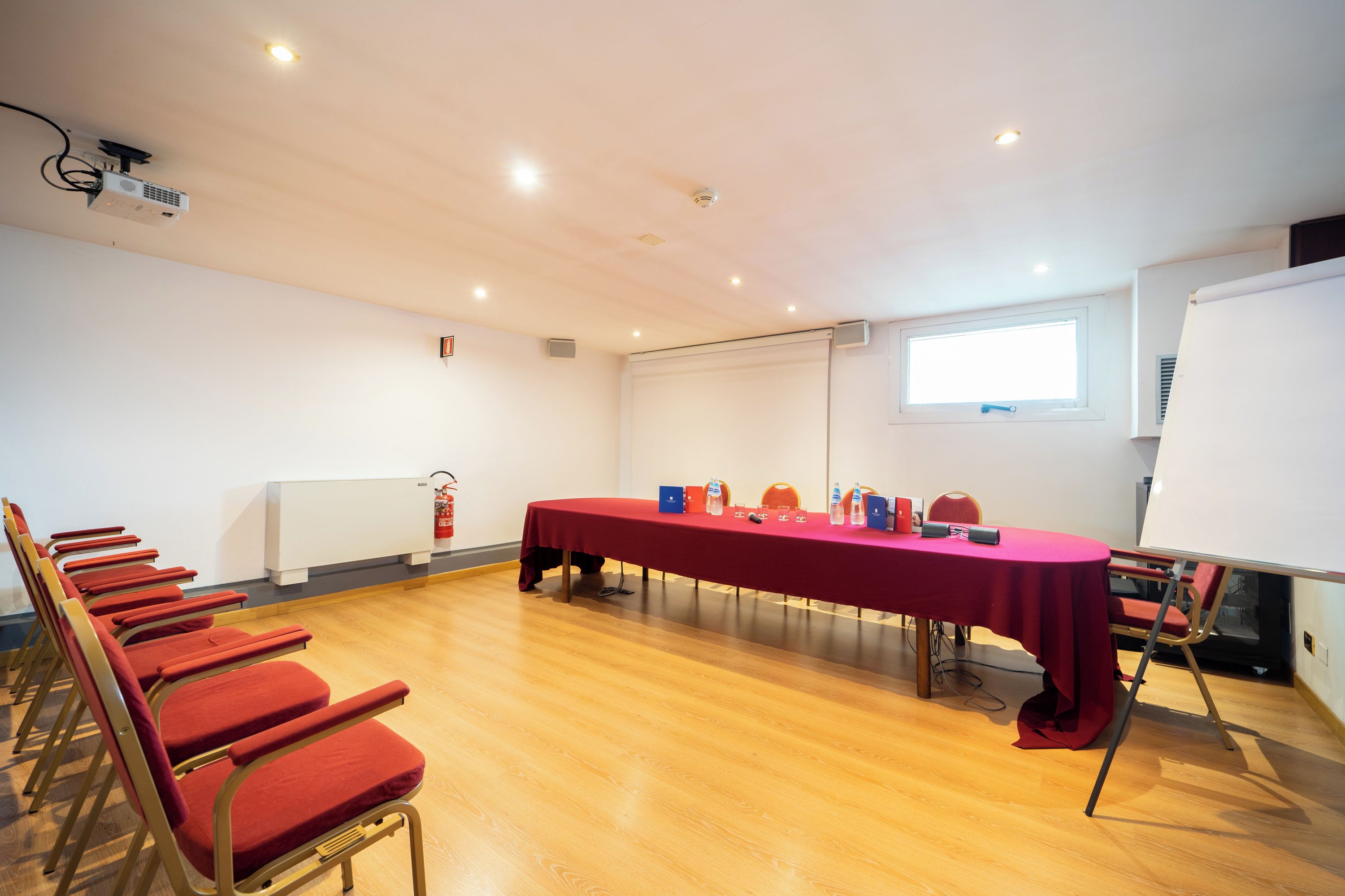 Una sala de conferencias con una mesa larga, sillas, una pizarra y una ventana.