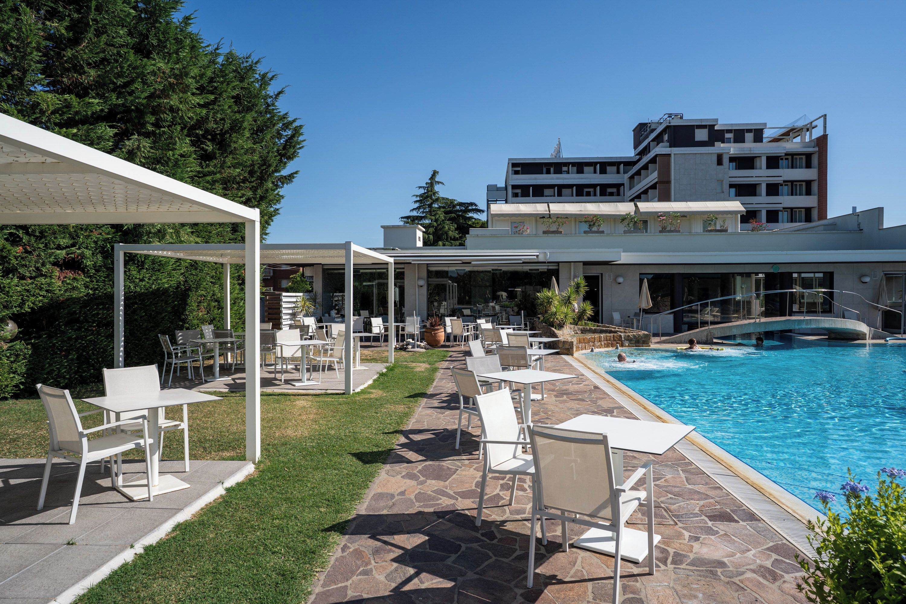 A poolside area with outdoor seating and a view of a building in the background.