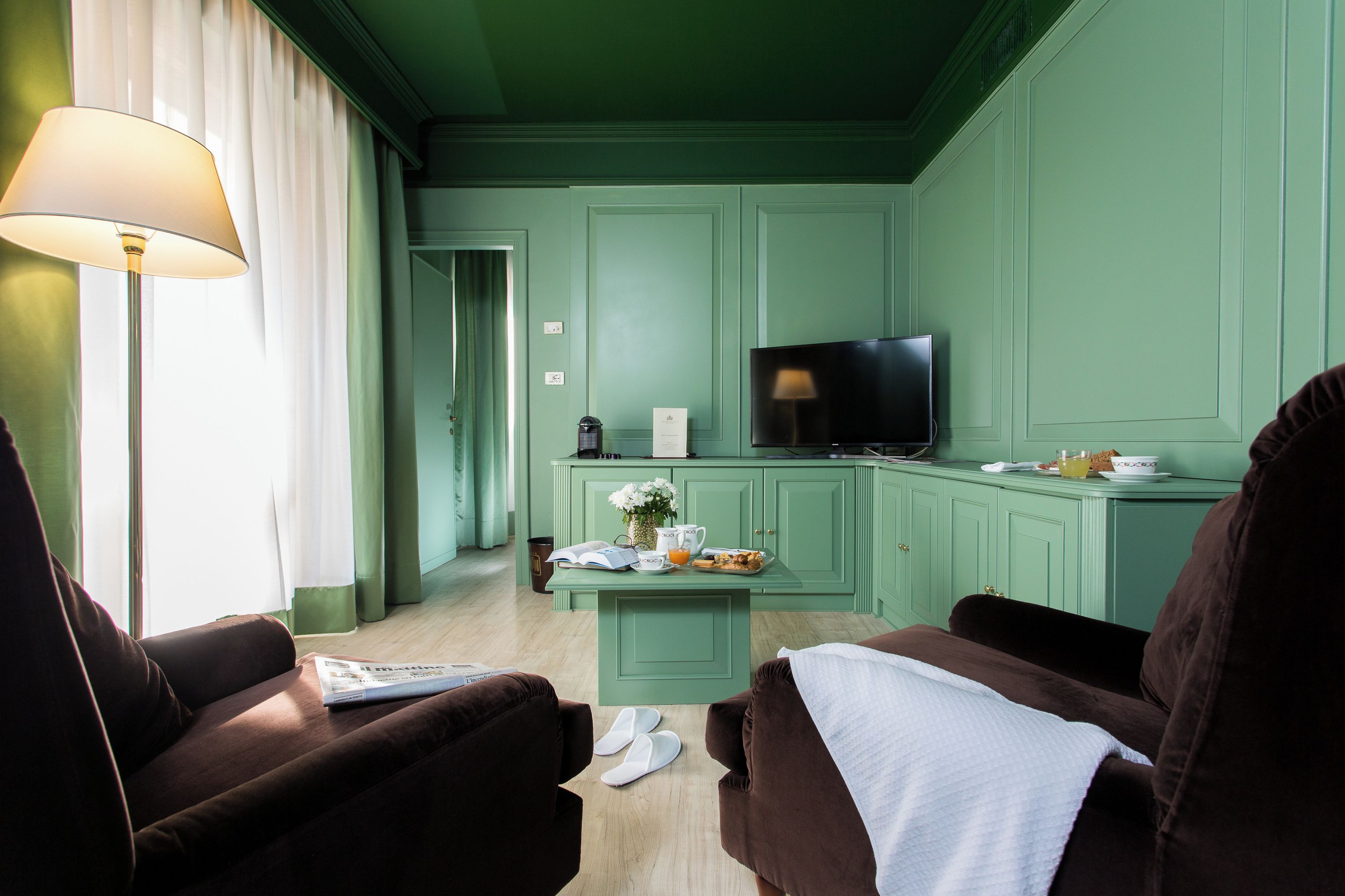 Une pièce équipée d’une télévision, d’une table basse avec des éléments pour le petit-déjeuner et de deux chaises.