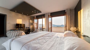 Une chambre d’hôtel moderne dotée d’un grand lit, d’un bureau et d’une télévision. La chambre dispose de grandes fenêtres offrant une vue sur les montagnes.