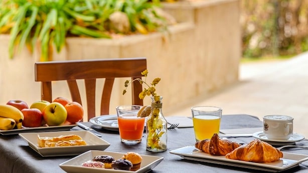 A breakfast setting with fruits, pastries, juice, and coffee on a table outdoors. - Nuova Barcaccia (Peschiera del Garda)