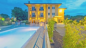 Un hôtel doté d’une piscine, d’un jardin bien entretenu et d’un bâtiment à deux étages avec des balcons.