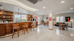 A modern kitchen with a bar area, wooden chairs, and a dining table. - Nuova Barcaccia (Peschiera del Garda)