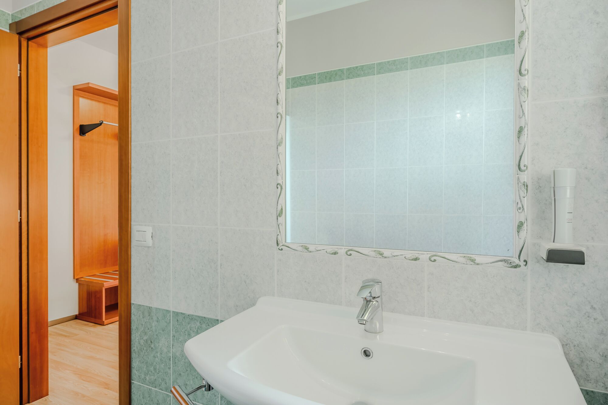 Une salle de bain avec un lavabo blanc, un miroir et un espace douche.