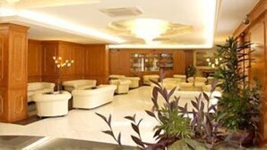 A spacious lobby with a high ceiling, wooden paneling, and multiple seating areas. - Capys (Capua)