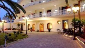 A hotel with a central courtyard, multiple balconies, and outdoor lighting. - Capys (Capua)