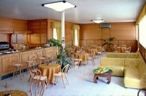 A spacious living area with a kitchen, dining tables, and a sofa. - Capys (Capua)