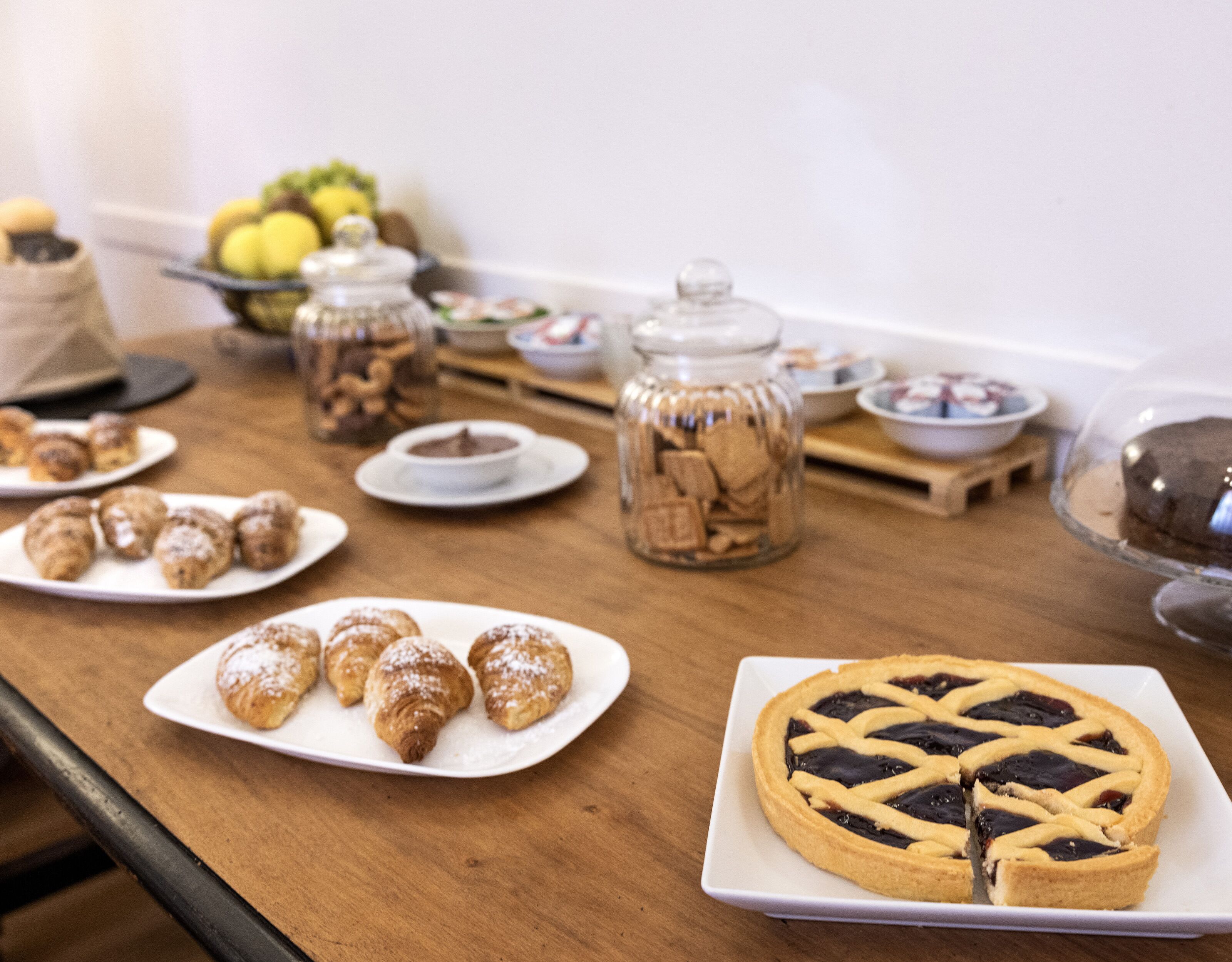 Una mesa con pasteles, un pastel y frascos de galletas.