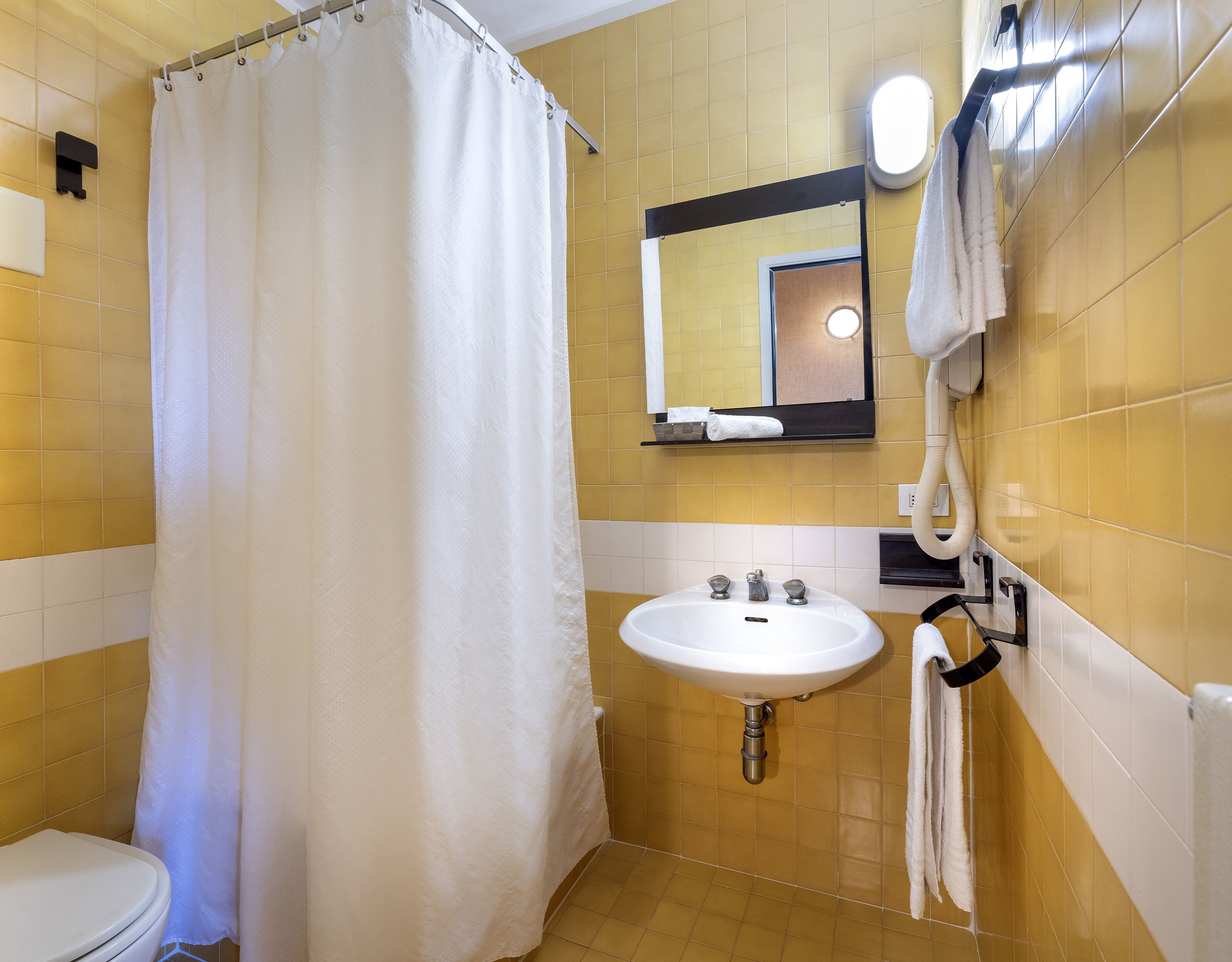 A bathroom with a white toilet, a sink, and a shower curtain.