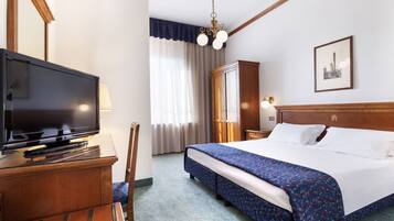 A hotel room with a bed, a TV, a desk, and a chair.