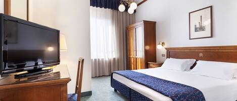 A hotel room with a bed, a TV, a desk, and a chair.