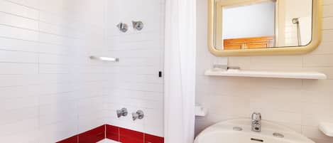 A bathroom with a shower, a sink, and a mirror.