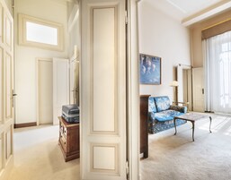 Een ruime woonkamer met een bank, een bijzettafeltje en een houten kast.