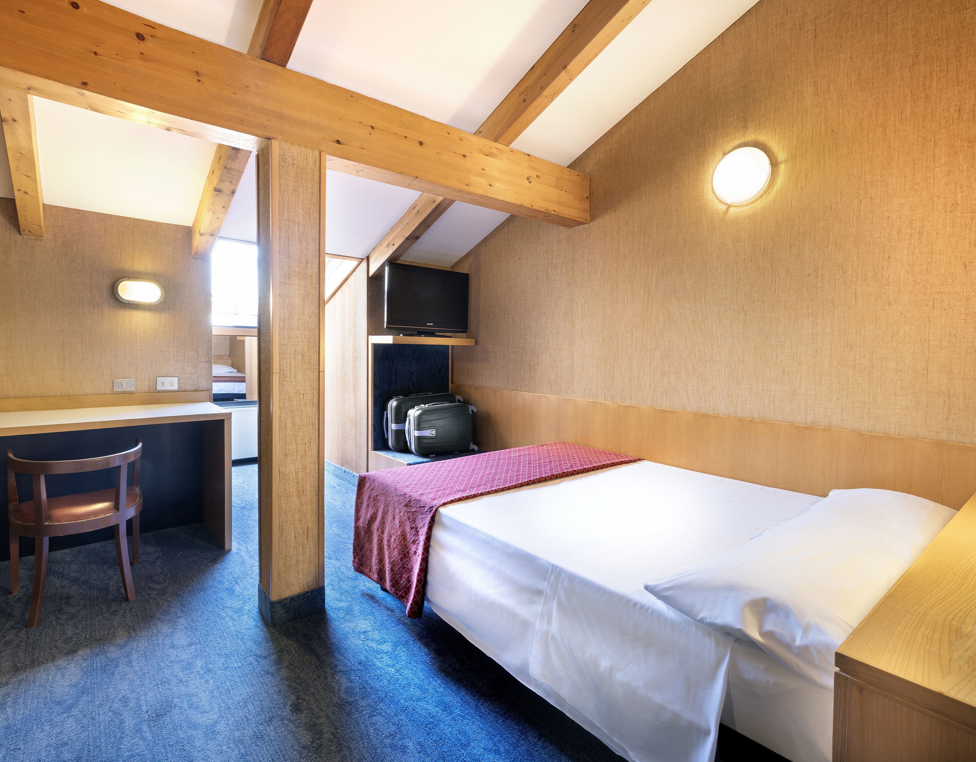 Une petite pièce comprenant un lit, un bureau, une chaise et un téléviseur.