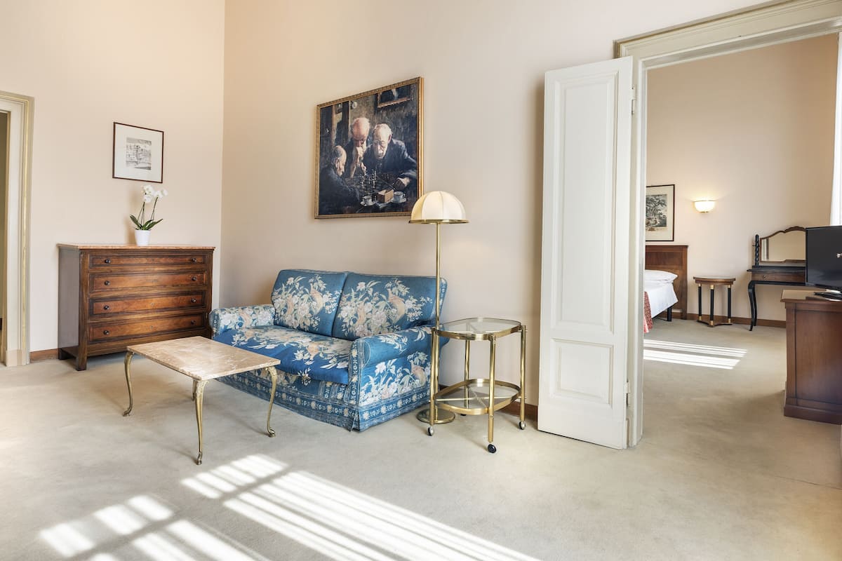 A living room with a blue sofa, a wooden dresser, a small table, and a lamp.