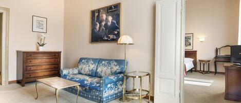 Ein Wohnzimmer mit einem blauen Sofa, einem Holzschrank, einem kleinen Tisch und einer Lampe.