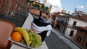 A balcony with a plate of fruit, a bottle, and a black bag. - Hotel Palace Bologna Centro (Bologna)