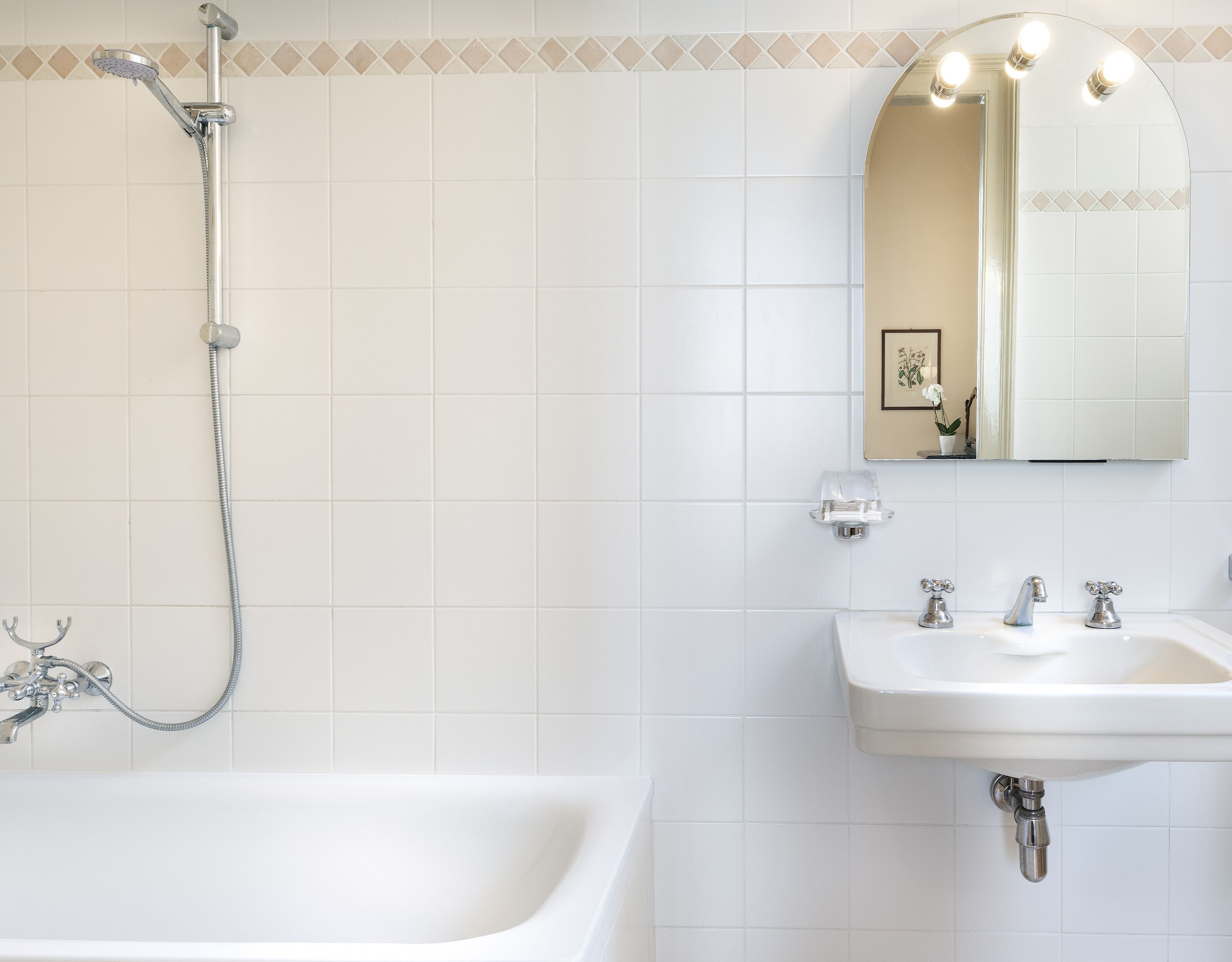 A bathroom with a bathtub, a shower, a sink, and a mirror.