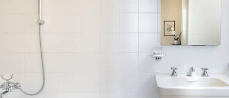 A bathroom with a bathtub, a shower, a sink, and a mirror.