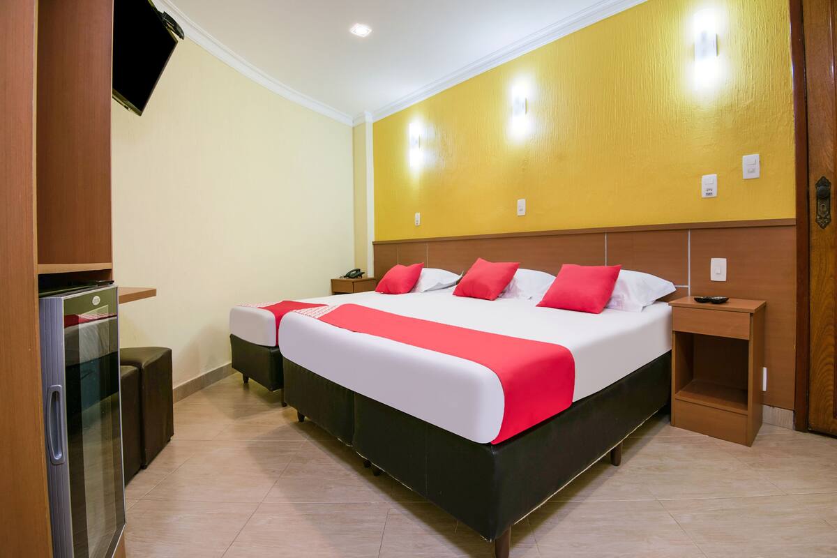 Une chambre d’hôtel avec un grand lit, une télévision, un bureau et un réfrigérateur.