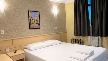 A hotel room with a bed, bedside table, and a wall-mounted picture.
