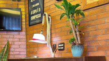 Un mueble de madera con cajones, un reloj de pared, un cuadro enmarco y una planta en maceta.