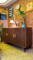 Ein Holzschrank mit Schubladen, eine wandmontierte Uhr, ein gerahmtes Bild und ein Blumentopf.