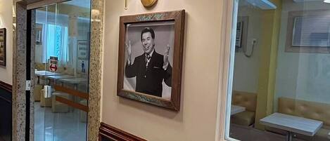 A hallway with a framed portrait, a lamp, and a window with a sign.