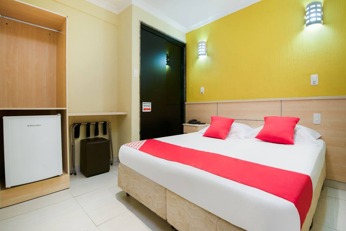 Une chambre d’hôtel équipée d’un lit, d’une armoire, d’un mini-bar et d’une porte avec une pancarte.