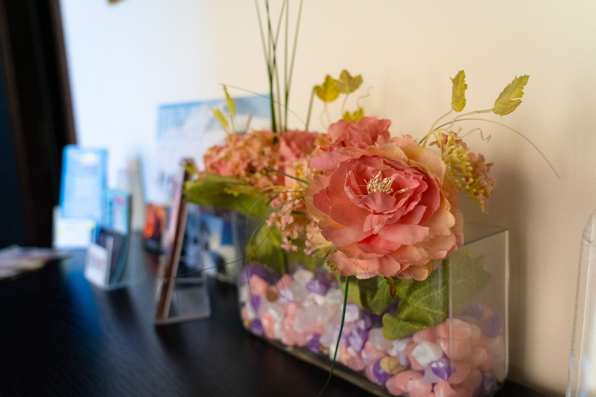 Un arrangement floral dans un vase en verre transparent, posé sur une étagère.