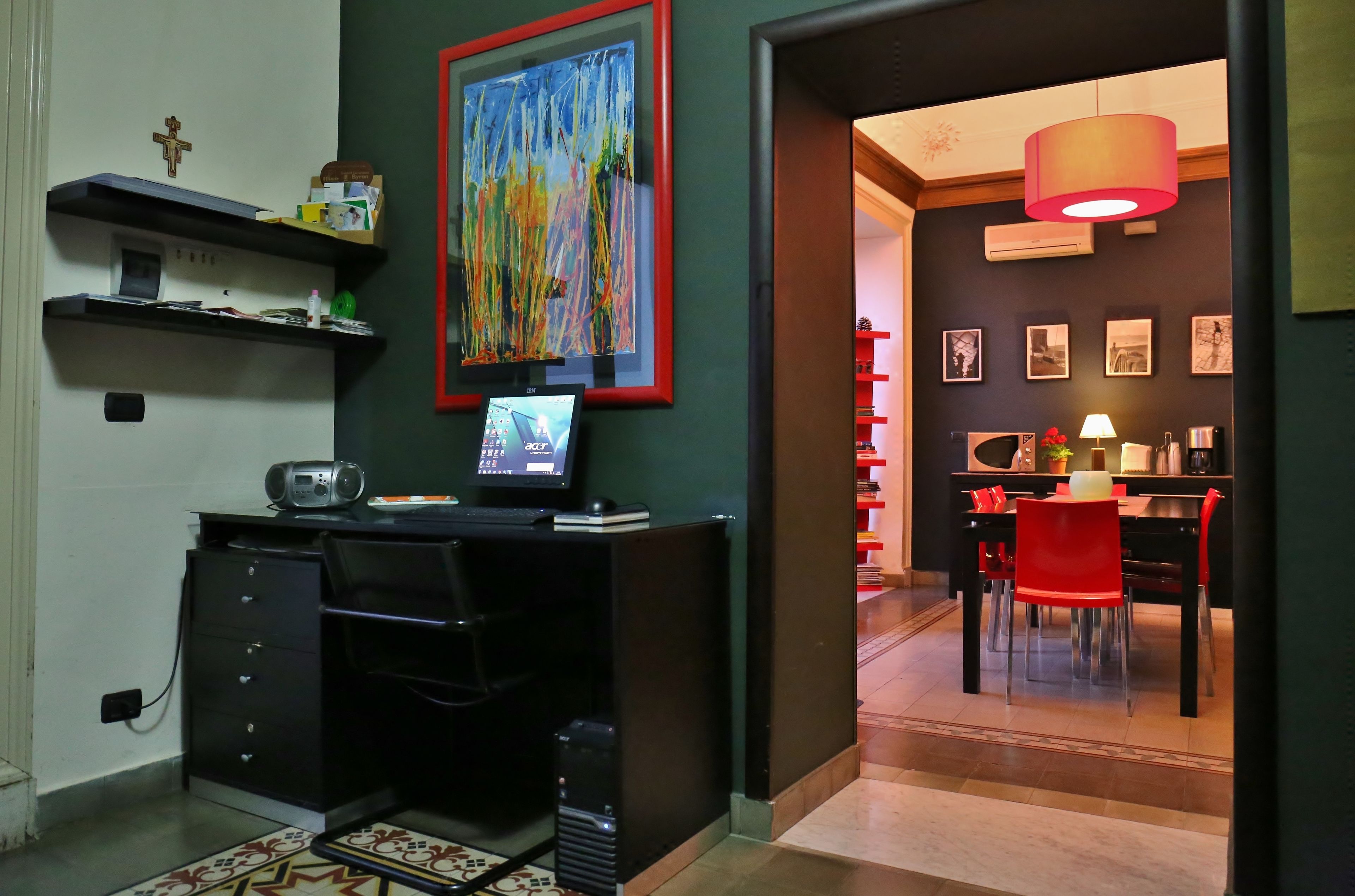 A modern living room with a black entertainment unit, a large abstract painting, and a dining area with red chairs and a table.