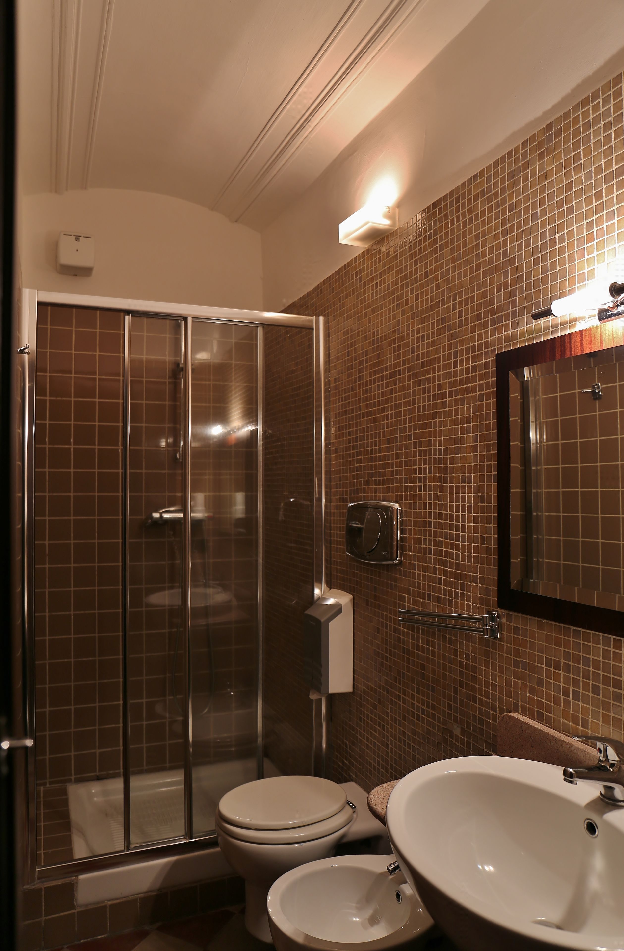 A bathroom with a glass shower enclosure, a toilet, and a sink with a mirror above it.