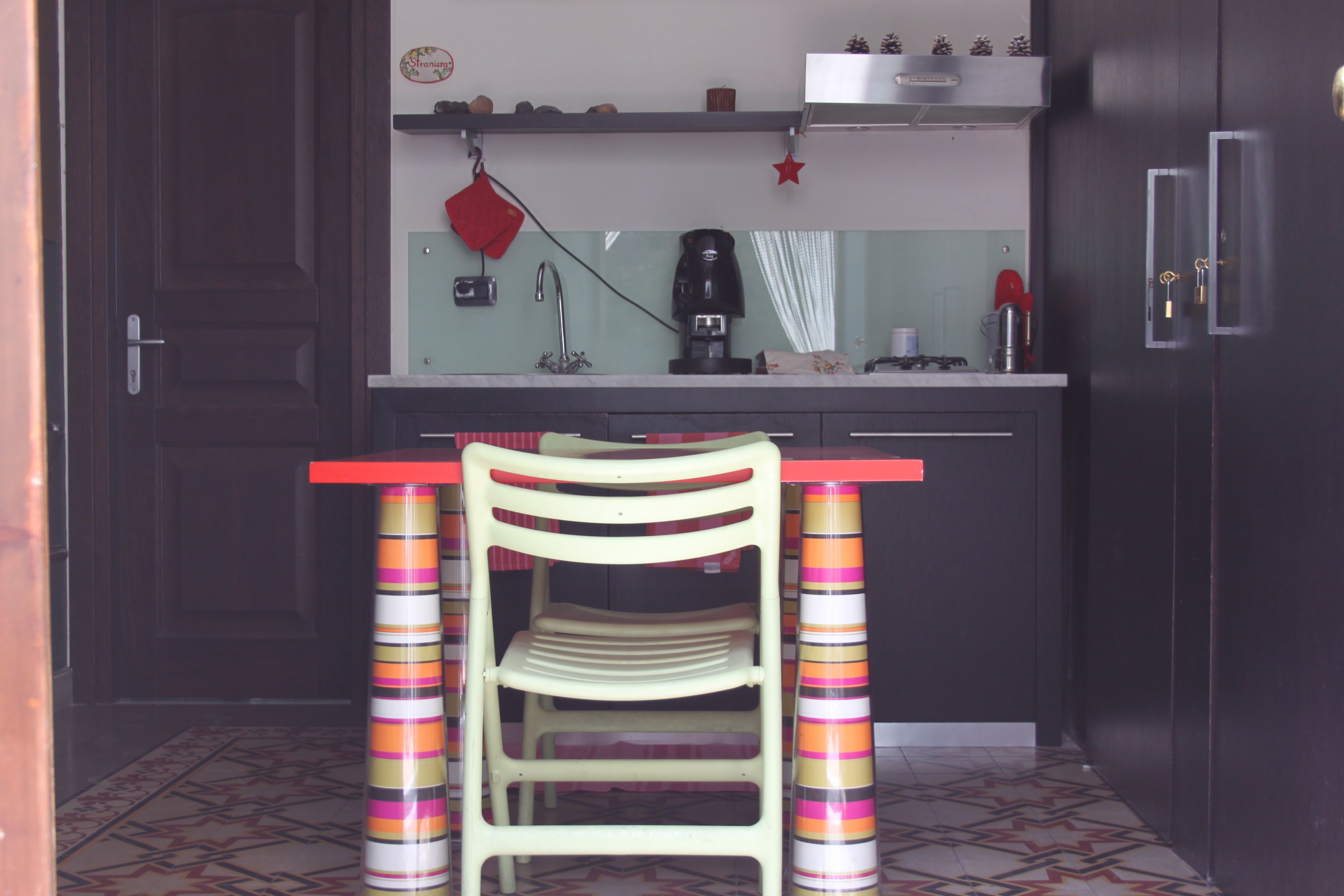 Una cocina con una silla de madera, una encimera y una cafetera.