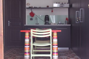 Una cucina con una sedia di legno, un piano di lavoro e una macchina per il caffè.