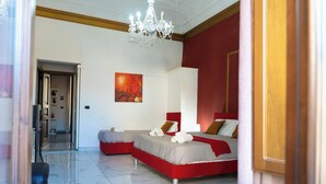 Habitación de hotel con una decoración en rojo y blanco, dos camas, una araña y un cuadro en la pared.