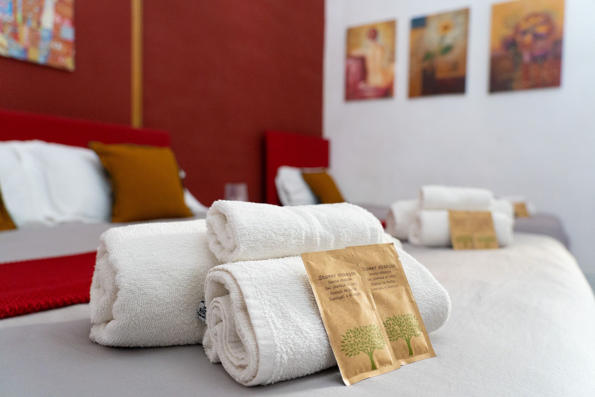 Un lit bien fait, avec des serviettes blanches et un sac en papier brun portant une inscription, qui contient probablement des articles de toilette.