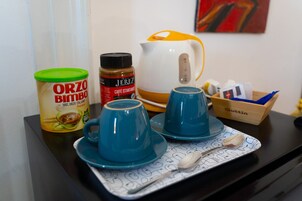Un tavolo con una macchina da caffè, un barattolo di caffè, una tazza di caffè e un cucchiaino su un vassoio.