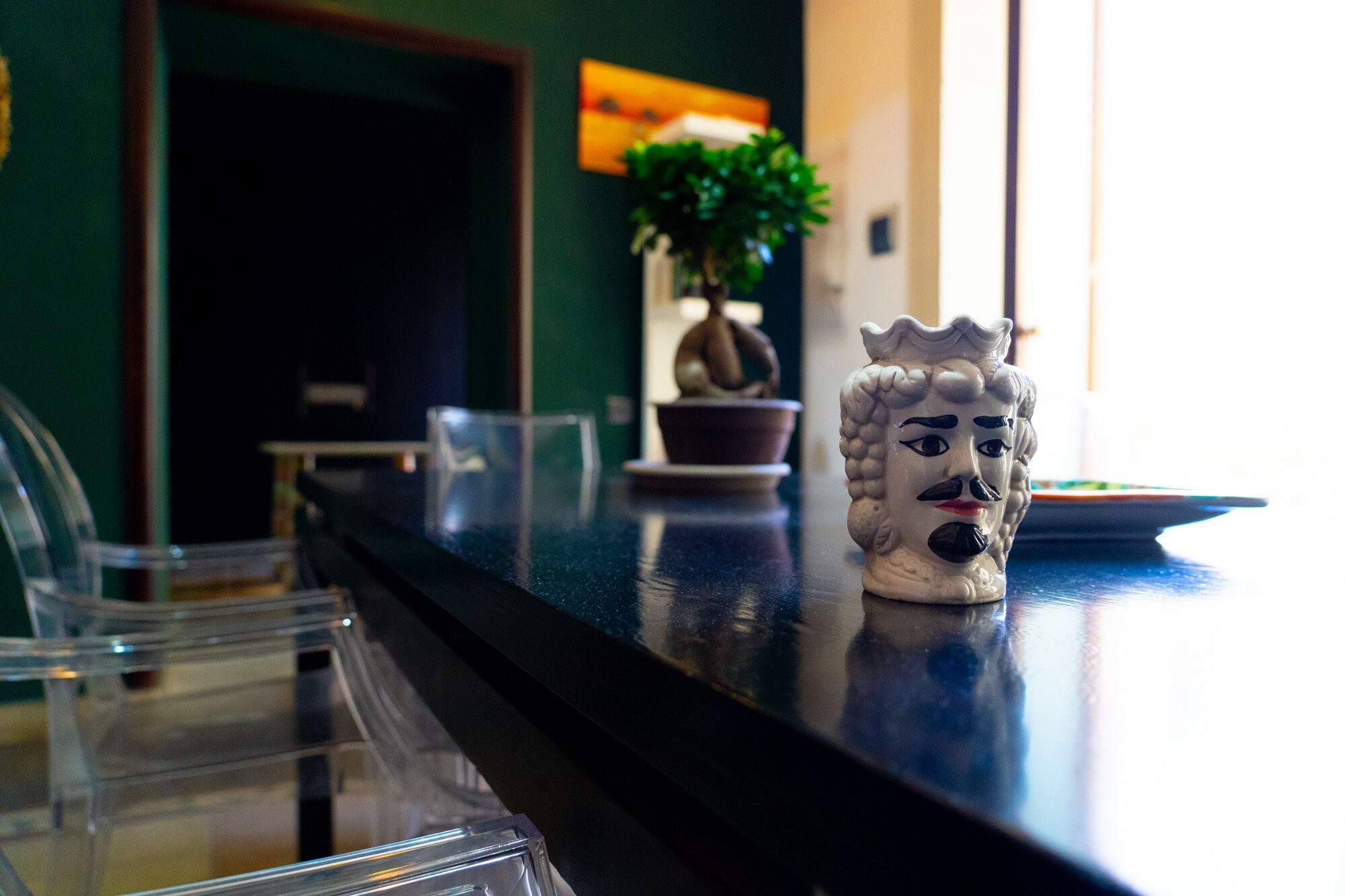 A bar area with a decorative ceramic figure, a potted plant, and a glass container.